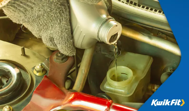 A technician pours brake fluid into the master cylinder reservoir.