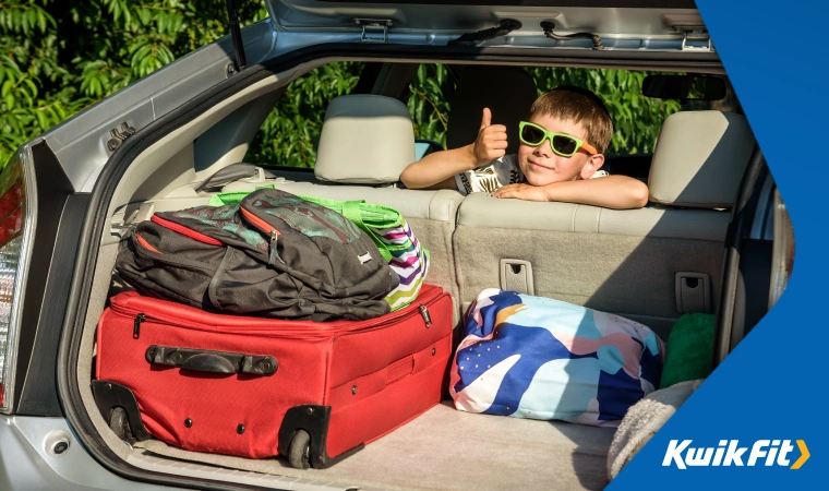 A family car with neatly packed luggage and a child in the backseat.