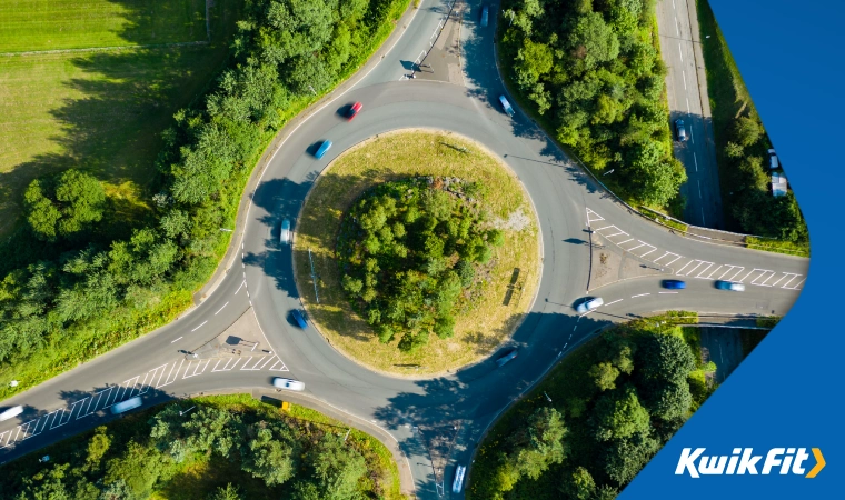 A 4 way roundabout surrounded by greenery.