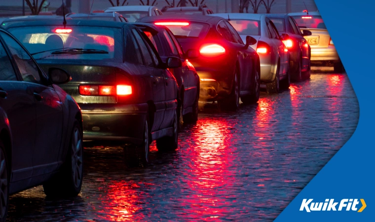 Traffic stuck in rain at night as lights reflect on road.